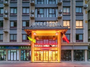 L’entrée d’un hôtel, conçue dans un style architectural chinois traditionnel, avec un toit recouvert de tuiles et une enseigne en caractères chinois.