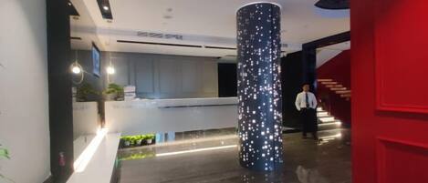 Et receptionsområde med et moderne design, en receptionsdisk og en stor søjle med lys.