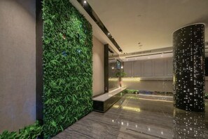 Un hall con jardín vertical verde, suelo de mármol y una moderna recepción.