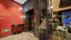 A modern lobby with a red wall, a staircase, and a round metal table with a plant. - Shangyuan Chain Hotel Guangzhou Railway Station (Guangzhou)