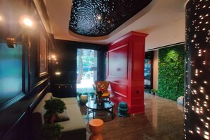 A modern interior with a red accent wall, a seating area with a sofa and chairs, and a green wall with plants. - Shangyuan Chain Hotel Guangzhou Railway Station (Guangzhou)