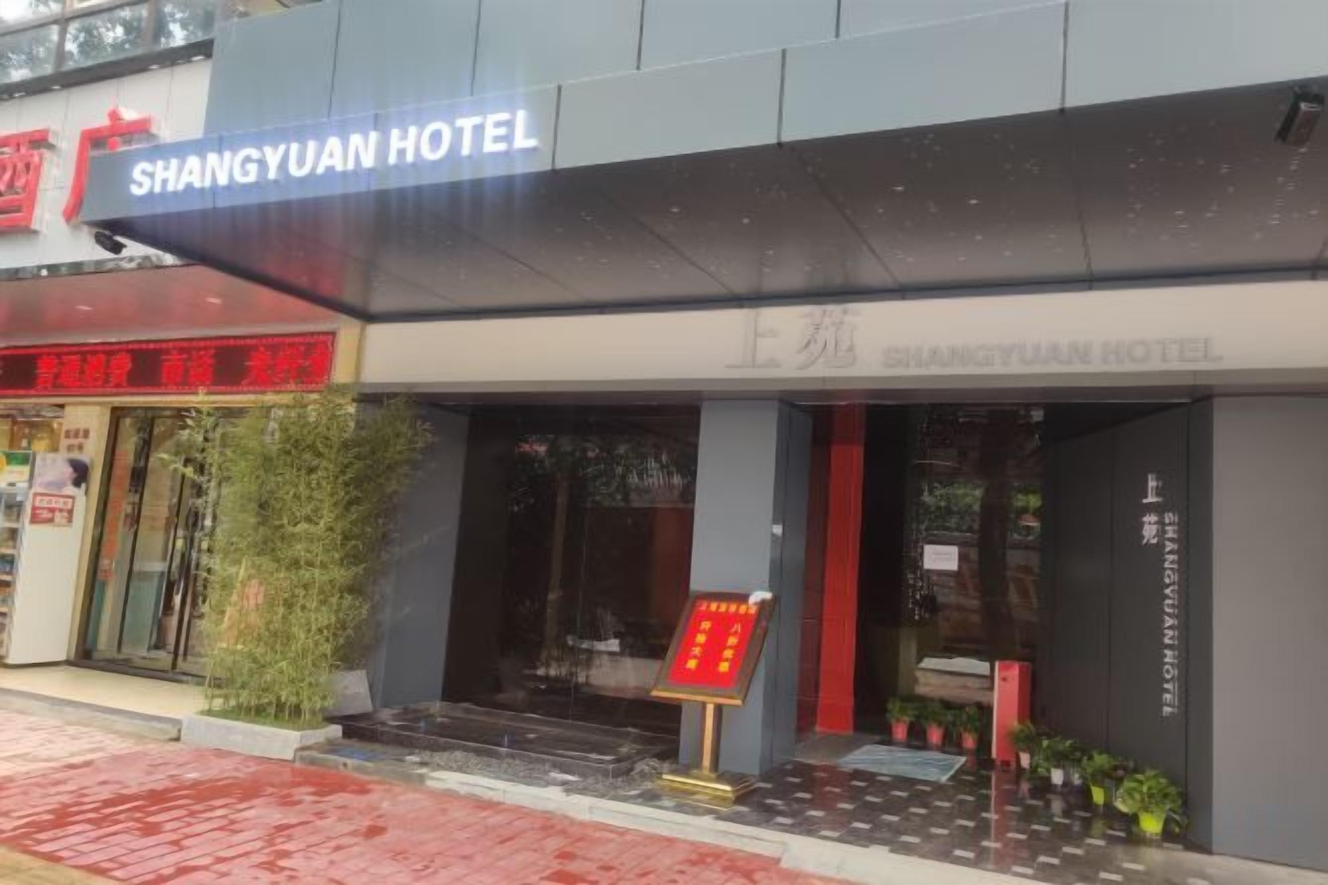A hotel entrance with a sign reading 'SHANGYUAN HOTEL' and a red signboard in front.