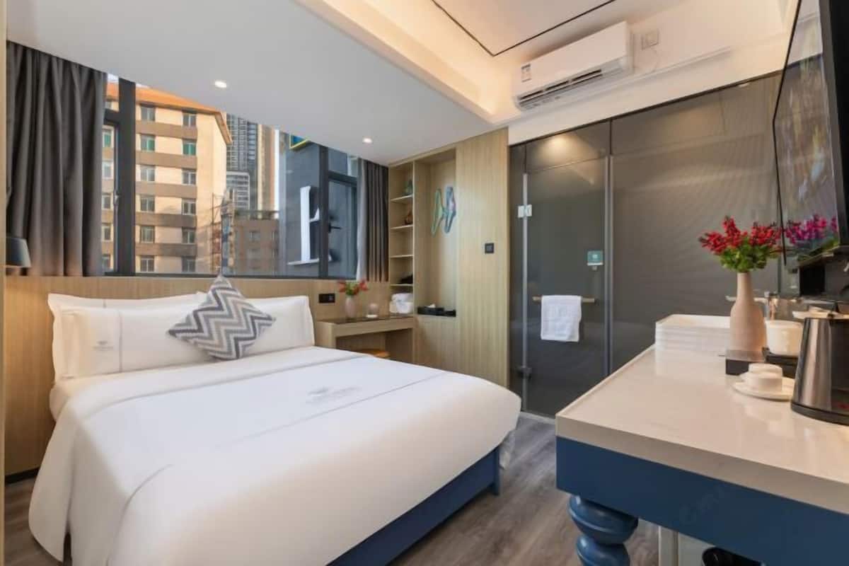 Ein Hotelzimmer mit Bett, Schreibtisch, Spiegel und Blick auf die Stadtlandschaft.