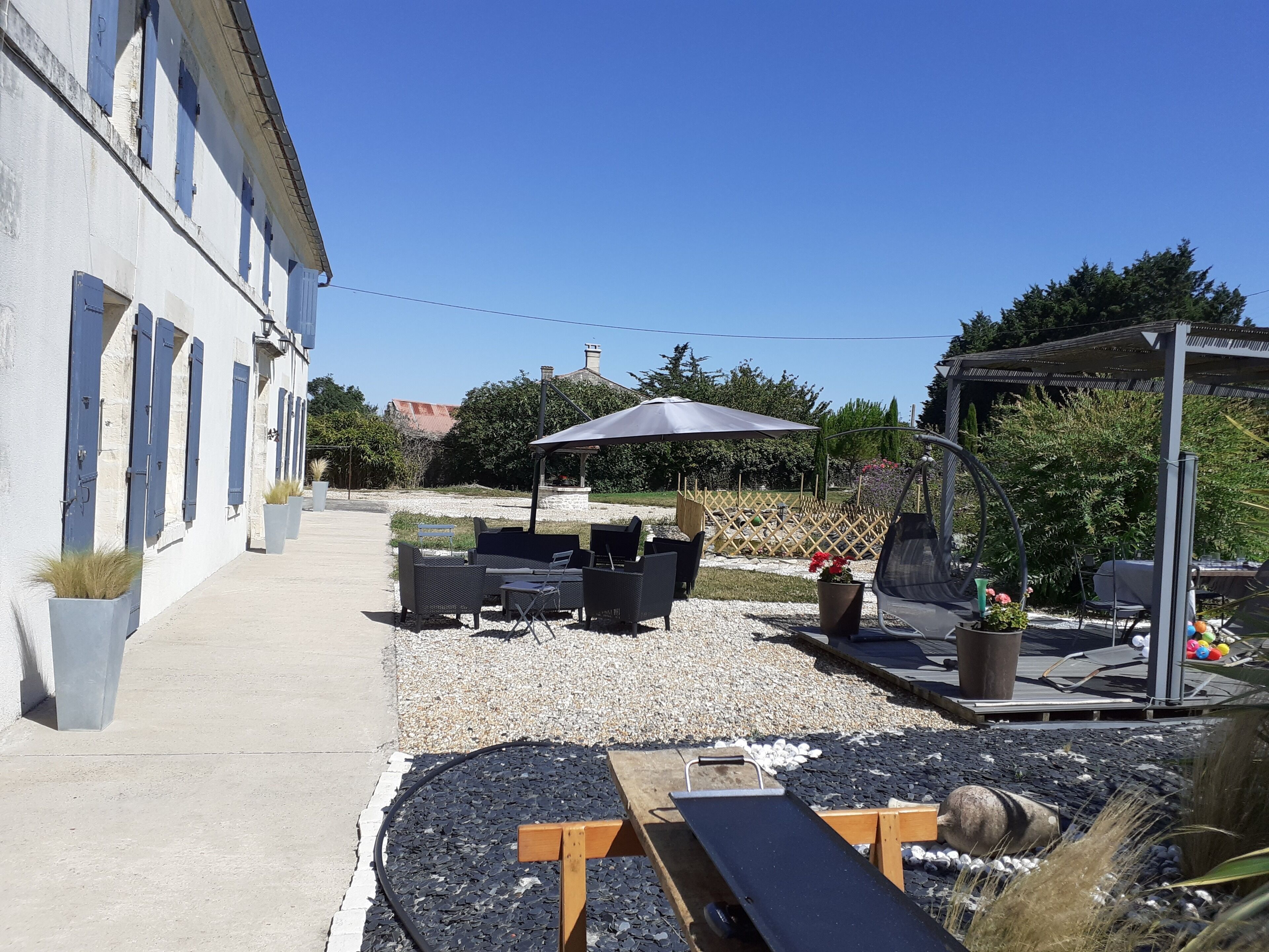 A patio area with outdoor seating, a pergola, and a garden setting.