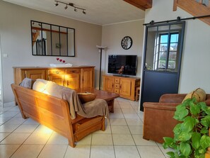 Una sala de estar acogedora con muebles de madera, un televisor y un ventanal grande.