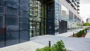 A modern building with large glass windows and a paved walkway.