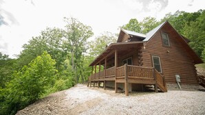 A wooden cabin with a porch, surrounded by trees and gravel path. - Gorgeous, tree top views from this cabin (Stanton)