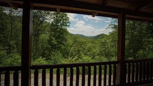 A covered outdoor area with a view of a forested valley. - Gorgeous, tree top views from this cabin (Stanton)