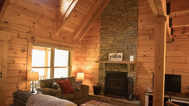 A cozy log cabin interior with a fireplace, a sofa, and a television. - Gorgeous, tree top views from this cabin (Stanton)