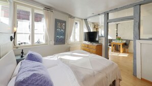 Une chambre à coucher comprenant un lit, un téléviseur, une commode en bois et un coin repas avec une table et des chaises.