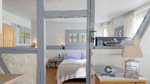 Une chambre à coucher avec un lit, des tables de chevet, une commode, une lampe et un miroir.