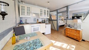 Une cuisine avec des meubles blancs, une table à manger en bois et une commode à tiroirs.