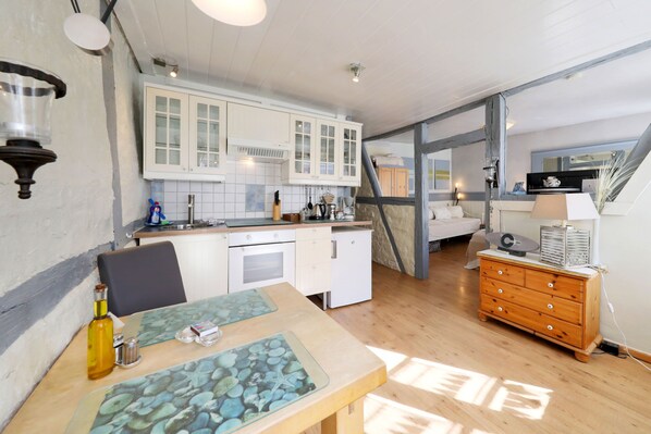 A kitchen with white cabinets, a wooden dining table, and a dresser with drawers.