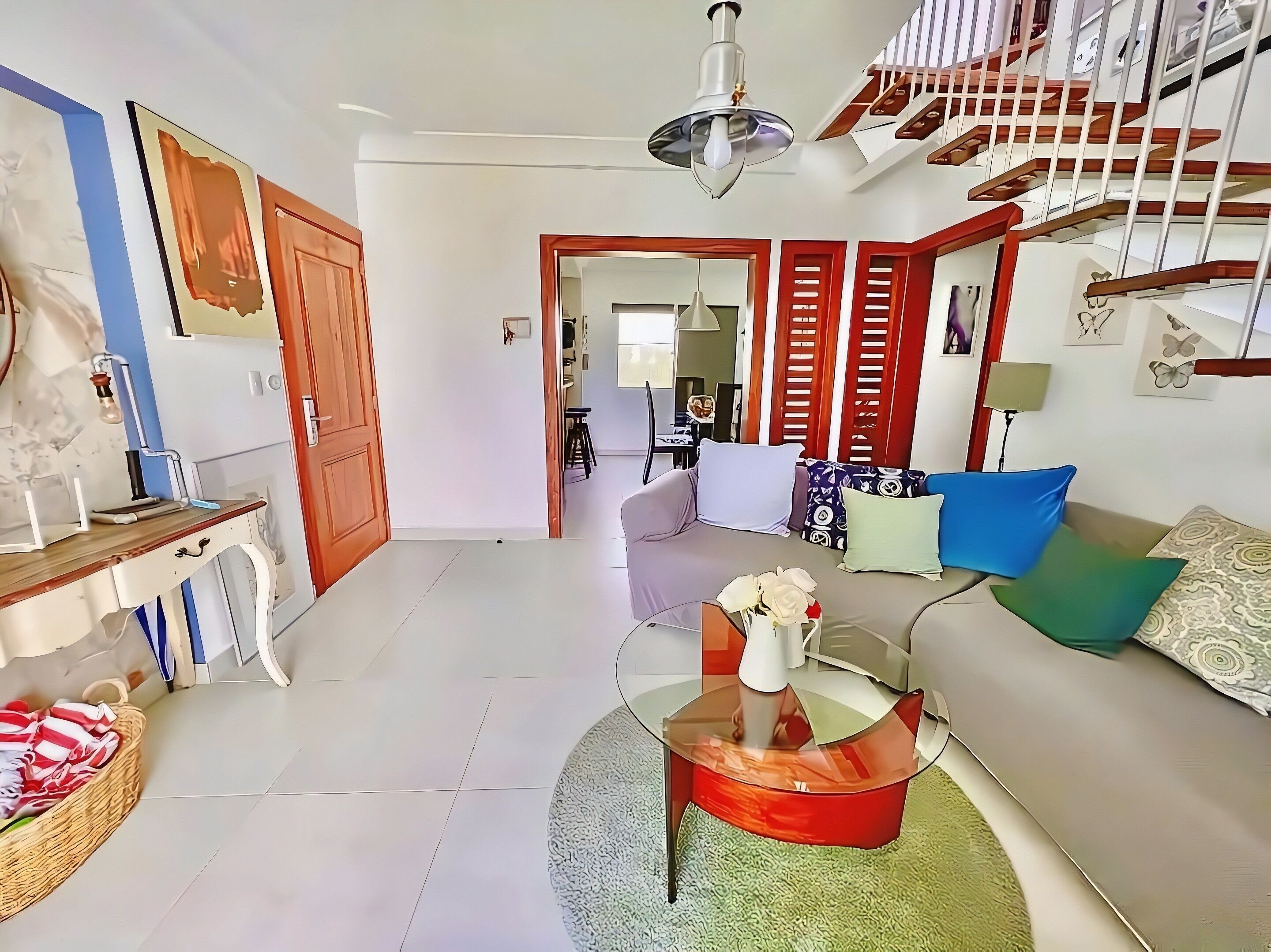 A living room with a sofa, a coffee table, a staircase, and a dining area.
