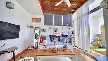 Una sala de estar con televisor, ventilador de techo y un comedor con mesa y sillas.