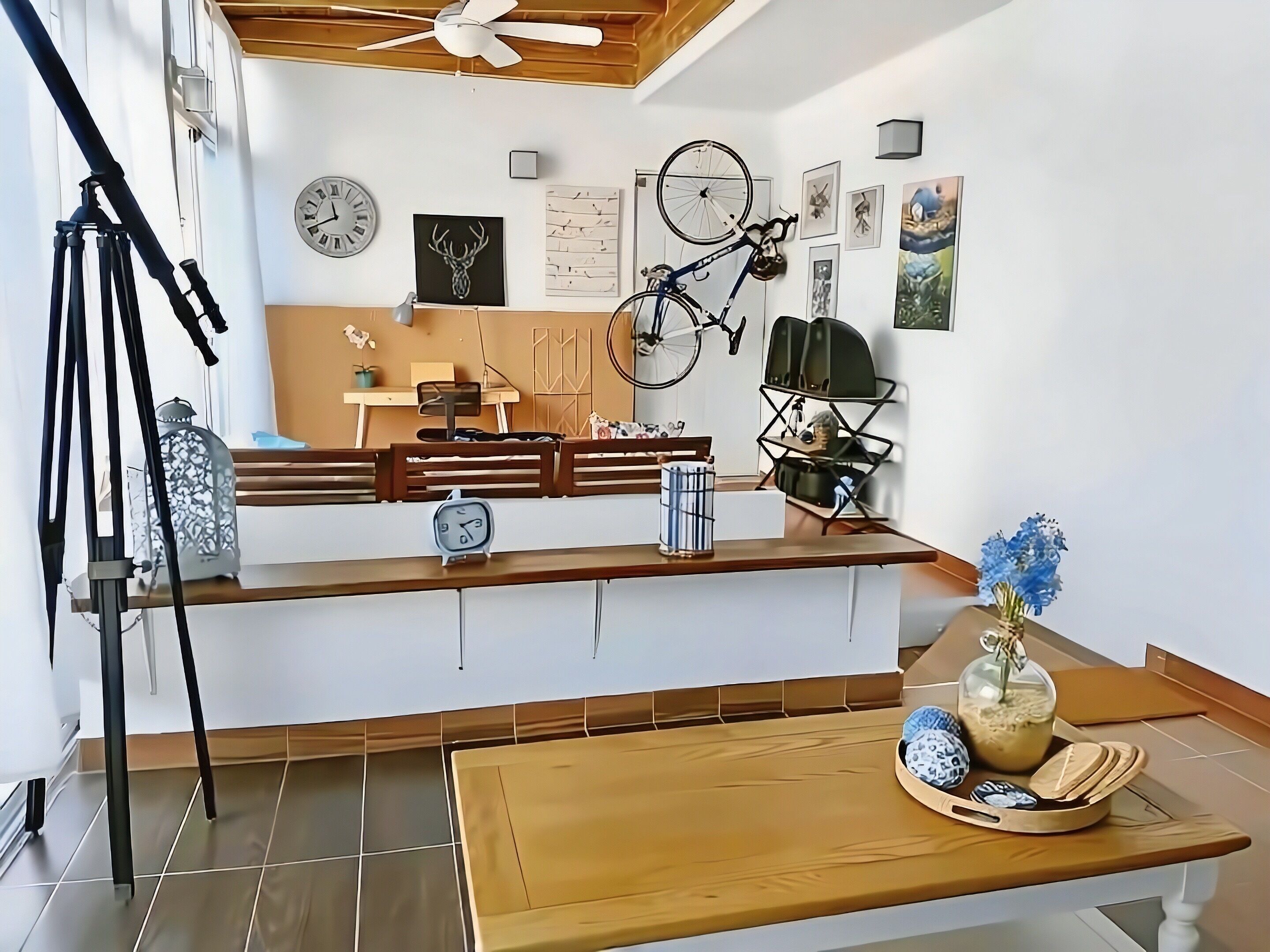 Una camera moderna con una panca di legno, una scrivania, una bicicletta e una sveglia a parete.