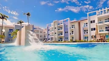 Una piscina con fuente, rodeada de edificios de varios pisos con balcones y áreas de estar al aire libre.