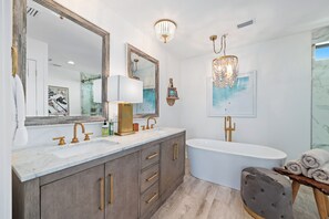 Un baño moderno con un espejo grande, dos lavamanos, una bañera y un mueble tocador con cajones.