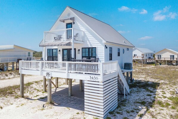 Una casa blanca frente a la playa con un balcón, una terraza y un cartel con el número 3451.