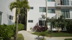A modern building with multiple balconies, a paved walkway, and various plants. - Wonderful Caribbean !!! (Playa del Carmen)