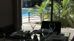 A dining table set with plates, glasses, and cutlery, overlooking a pool and palm trees. - Wonderful Caribbean !!! (Playa del Carmen)