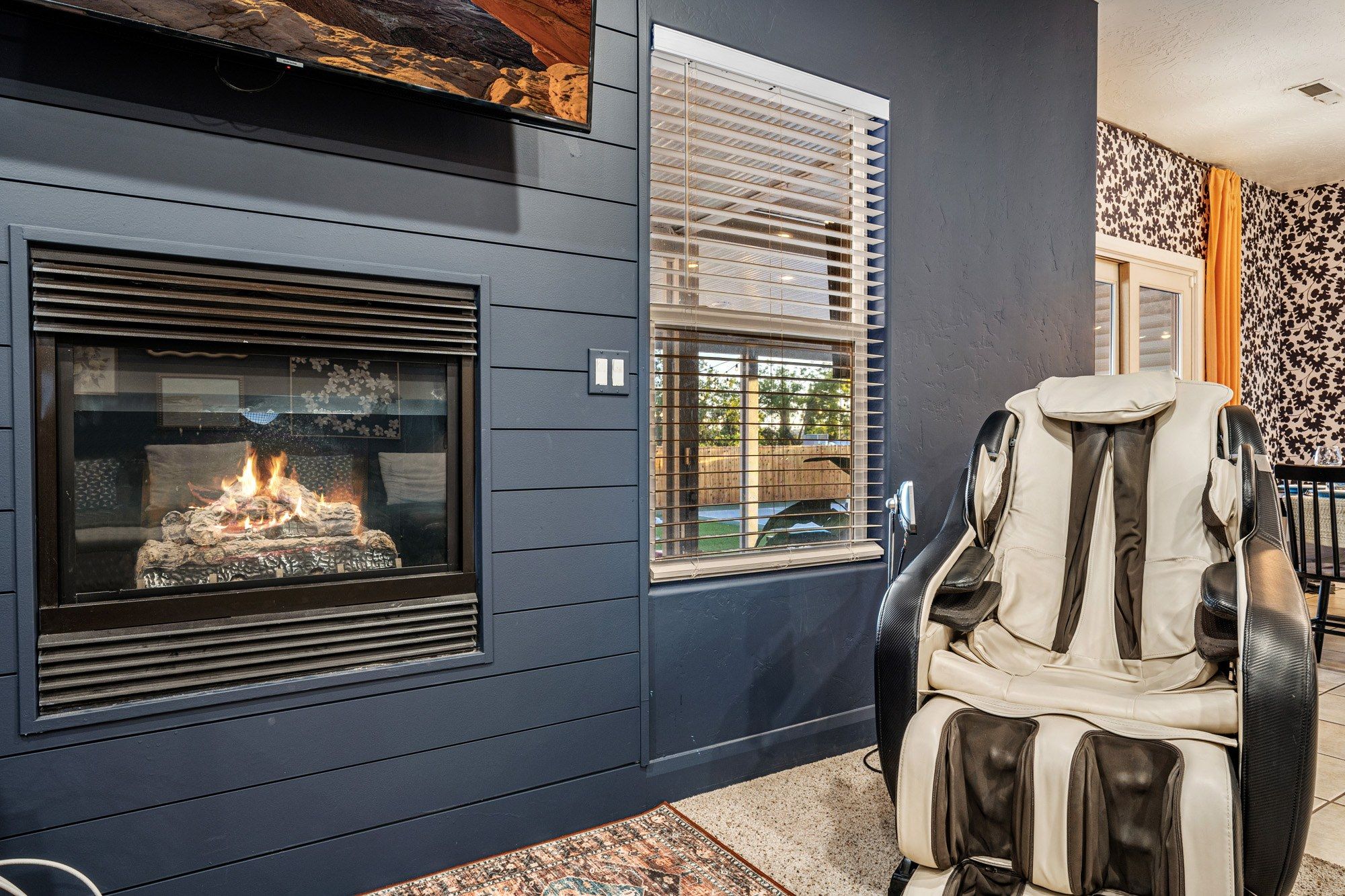 A modern outdoor seating area with a fireplace, a cushioned chair, and a patterned rug.
