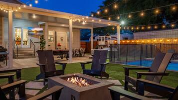 An outdoor patio area with a fire pit, seating, and string lights.