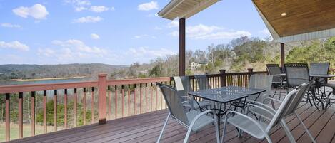 A wooden deck with outdoor furniture, a view of a lake, and a covered area with a roof.
