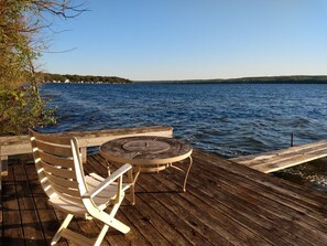 En træterrasse med et bord og to stole med udsigt over en sø.