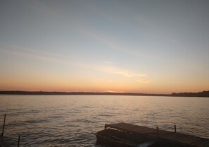 En rolig sø ved solnedgang med en træbro, der strækker sig ud i vandet.