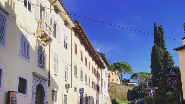 Una calle adoquinada flanqueada por edificios históricos, con un coche estacionado al costado y una señal de paso para peatones.