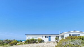 A modern white building with a blue roof, situated on a sandy beach with clear blue skies. - Kalimna - 360 degree ocean and marina views! (Robe)