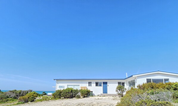 A modern white building with a blue roof, situated on a sandy beach with clear blue skies. - Kalimna - 360 degree ocean and marina views! (Robe)