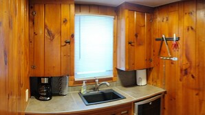 Una cocina con paneles de madera, un fregadero, una cafetera y un refrigerador.