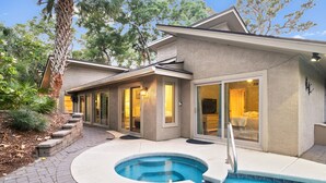 Una casa moderna con piscina, un patio cubierto y un jardín bien cuidado.