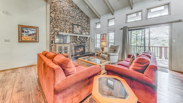 A spacious living room with a stone fireplace, a large window, and a cozy seating area. - Spacious Ruidoso Retreat: Game Room & Pool Access! (Ruidoso)