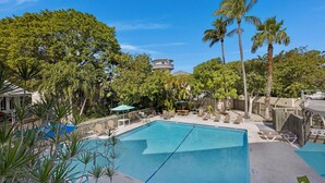 A swimming pool with lounge chairs and umbrellas, surrounded by palm trees and a building with a round tower. - **SET SAIL @ COCONUT MALLORY** Condo + Last Key White Glove Service... (Key West)