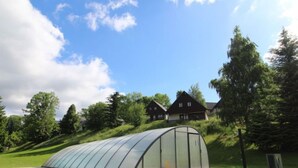 Ein Gewächshaus in einer grünen Umgebung, mit einem Weg davor.