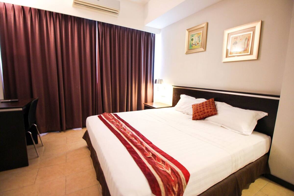 Una habitación de hotel con cama, escritorio, silla y cortinas.