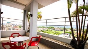 Un balcon avec une table et des chaises, offrant une vue sur le paysage urbain et la verdure.
