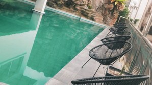 Une piscine sur le toit, avec une eau cristalline, entourée d’un bâtiment blanc et d’une falaise rocheuse.