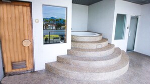 Un escalier en pierre mène à un espace de détente avec vue sur les palmiers et les montagnes.