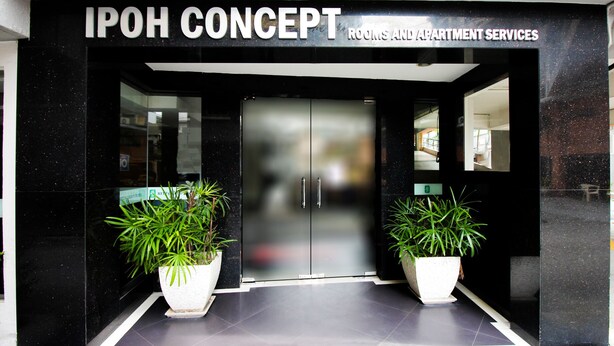 L'entrée d'IPOH CONCEPT présente un design moderne, avec deux grands pots de plantes et une porte vitrée donnant accès à l'intérieur.