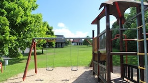 Ein Spielplatz mit Schaukeln und einer Kletterkonstruktion.