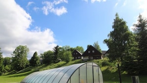 Ein Gewächshaus in einer grünen Umgebung, mit einem Weg davor.