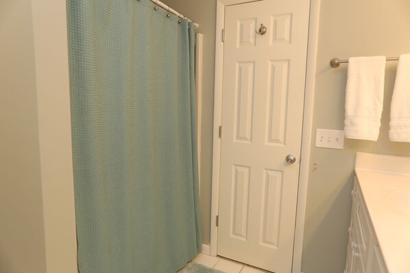 A bathroom with a shower curtain, a door, and a towel rack with towels. - Gulf Front, Newly Renovated ~ One More Time Again (Mexico Beach)