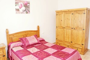 A bedroom with a wooden bed, a wooden wardrobe, and a small bedside table.