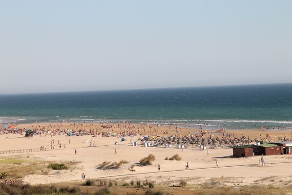 A beach with a sandy shore, umbrellas, and beachgoers.