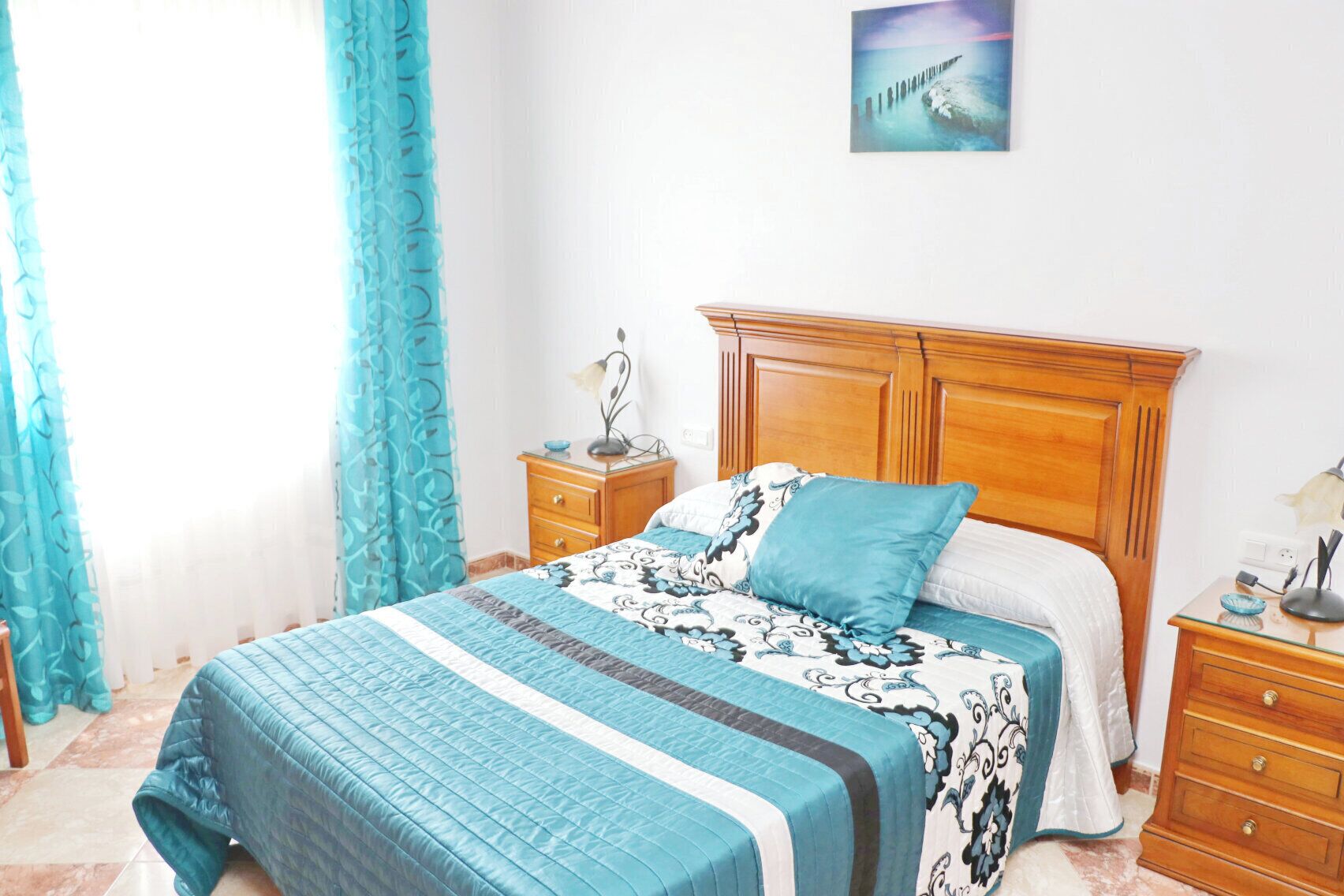 Ein Schlafzimmer mit einem Bett, einem Nachttisch, einer Kommode und einem Bild an der Wand.