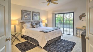 A bedroom with a bed, two bedside lamps, a ceiling fan, a window with a view, and a door. - Desert Oasis in La Quinta! Heated Pool & Patio (La Quinta)